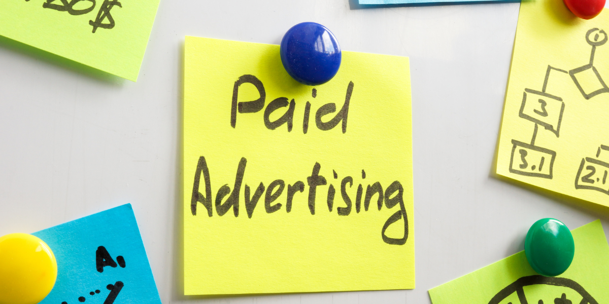 Yellow sticky note on a whiteboard saying paid advertising