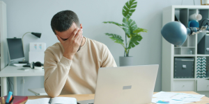 A man sitting at his laptop looking stressed